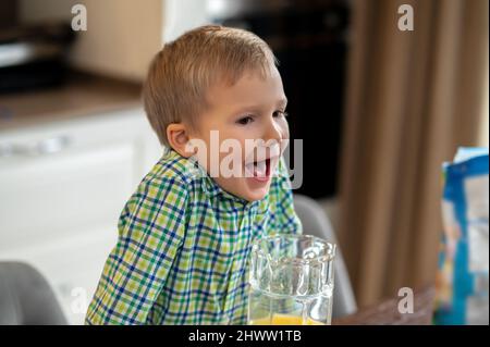 Kind mit offenem Mund auf dem Küchentisch gelehnt Stockfoto