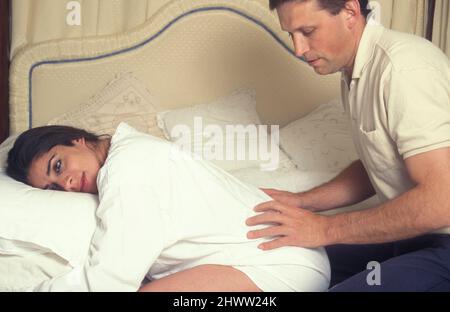 Mann, der dem Schwangeren hilft, sich während der Wehen zu entspannen Stockfoto