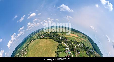 Luftaufnahme aus großer Höhe des kleinen Planeten Erde mit kleinen Dorfhäusern und entfernten grünen bebauten landwirtschaftlichen Feldern Stockfoto