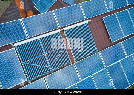 Gebäudedach mit Reihen von blauen Photovoltaik-Paneelen und Vakuum-Luft-Solarkollektoren für die Warmwasserbereitung und die Produktion von sauberem ökologischem Strom. Rene Stockfoto