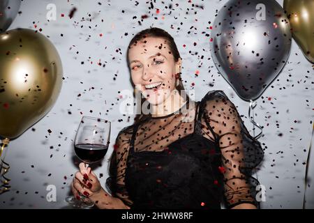 Waist-up-Porträt von unbeschwerten jungen Frau Party mit Konfetti fallen, mit Blitz geschossen Stockfoto