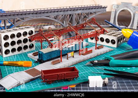Bau einer Modelleisenbahnanlage. werkbank mit Modelleisenbahnstation Brückengleise und Landschaftswerkzeuge. Hobby Freizeitmodellierung c Stockfoto