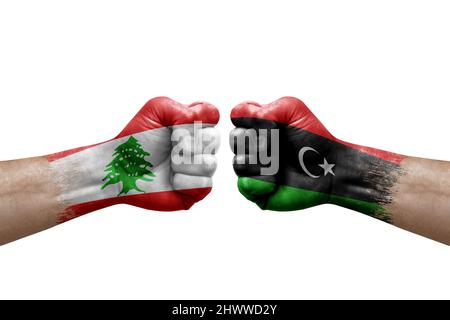 Zwei Hände schlagen sich gegenseitig auf weißem Hintergrund zu. Länderflaggen bemalten Fäuste, Konfliktkrisenkonzept zwischen libanon und libyen Stockfoto