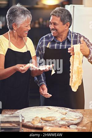 Dieser Nudelteig ist die perfekte Textur. Aufnahme eines reifen Paares, das zu Hause zusammen kocht. Stockfoto