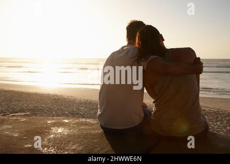 Das Leben ist perfekt mit dir an meiner Seite. Silhouette eines Paares, das am Strand nebeneinander sitzt. Stockfoto