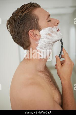 Glatte, gründliche Rasur. Ein hübscher junger Mann, der sich rasieren kann. Stockfoto