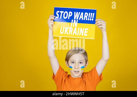 Ein trauriger Junge erhob ein Plakat mit der Aufschrift Stoppen Sie den Krieg in der Ukraine Stockfoto