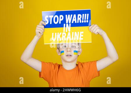 Ein trauriger Junge erhob ein Plakat mit der Aufschrift Stoppen Sie den Krieg in der Ukraine Stockfoto