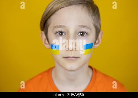 Porträt eines Jungen mit einer gemalten Flagge der Ukraine auf seinen Wangen Stockfoto