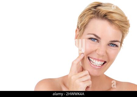 Perfekte Haut braucht viel Feuchtigkeitscreme. Kurzer Schuss einer wunderschönen jungen Frau auf Weiß isoliert und mit etwas Feuchtigkeitscreme auf ihr Gesicht auftragen. Stockfoto