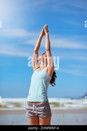 Die längste Reise einer Person ist die Reise nach innen. Aufnahme einer jungen Frau, die am Strand ihre Yoga-Routine praktiziert. Stockfoto