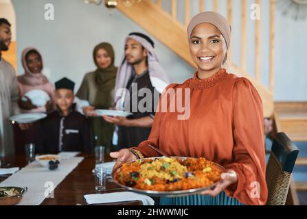 Kochen für meine Familie bringt mir Frieden. Aufnahme einer muslimischen Frau, die einen Teller mit Lebensmitteln in der Hand hält. Stockfoto