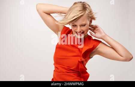 Schönheit in einem orangefarbenen Kleid. Eine attraktive junge Frau in einem roten Kleid. Stockfoto