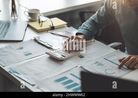 Nahaufnahme des Geschäftsmannes, der am Schreibtisch arbeitet, mit einem Rechner, der die Finanzbuchhaltung im Büro analysiert Stockfoto