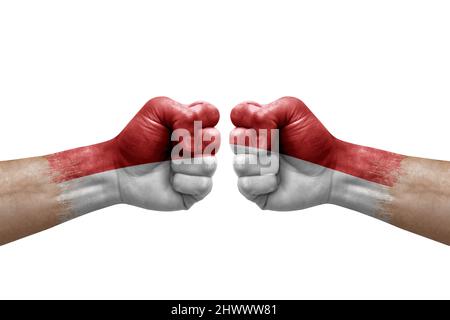 Zwei Hände schlagen sich gegenseitig auf weißem Hintergrund zu. Länderflaggen bemalten Fäuste, Konfliktkrisenkonzept zwischen monaco und monaco Stockfoto