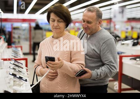 Seniorenpaar, das sich im Technikgeschäft für ein Smartphone entschieden hat Stockfoto