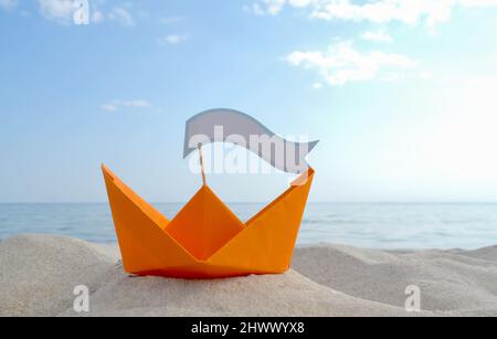 Orange Papier Boot auf Sandy Seashore Nahaufnahme kleines Boot aus Papier auf dem Hintergrund Stockfoto