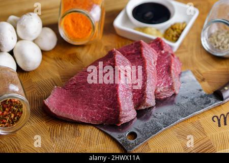 Roh, fertig zum Grillen von Rindersteaks auf Messern, Mashrooms-Gewürze auf Schneidebrett. Gesundes Lebensmittelkonzept Stockfoto