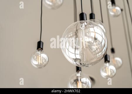 Moderne Innenbeleuchtung an der hohen weißen Decke, runde hängende Glühbirnen, leerer Raum, Bild aus der Wurmperspektive. Stockfoto