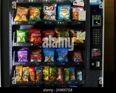 Amerikanische Snacks, Chips, Chips, Süßigkeiten und andere Junk-Food in einem Automaten mit bargeldlosen, Münzen- und Kartenzahlungsoptionen. Stockfoto