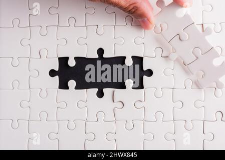 Draufsicht flach Lay von Hand halten letzten Stück weißes Papier Puzzle-Spiel letzte Stücke gelegt, um Platz für Problem lösen komplette Mission, Studio Schuss o Stockfoto