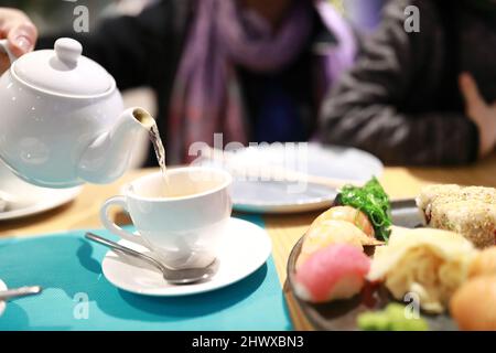 Person gießt grünen Tee in einem Restaurant Stockfoto