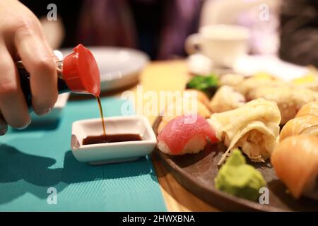 Person gießt Sojasauce im asiatischen Restaurant Stockfoto