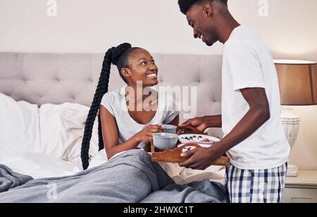 Man fühlt sich nicht wohl, also habe ich Frühstück gemacht. Aufnahme eines jungen Mannes, der seine Freundin zum Frühstück ins Bett brachte. Stockfoto