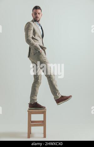 Konzept des Menschen in seinem 40s verlassen sein altes Leben hinter und tritt in neue Möglichkeiten, Blick über die Schulter auf grauem Hintergrund Stockfoto