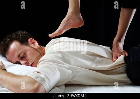 Nahaufnahme eines jungen Mannes, der eine barfuß-Rückenmassage erhalten hat. (MODELL FREIGEGEBEN) Stockfoto