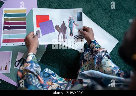 Junger Mann mit polierten Nägeln mit selbstgemachten Kunstwerken oder Collage aus geschnittenen älteren Frauen, Vase mit Blumen und Farbmustern Stockfoto