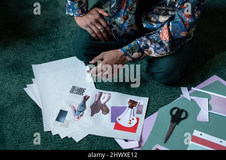 Nahaufnahme eines jungen kreativen Mannes, der an Papieren sitzt, mit selbstgemachten Collagen, bestehend aus Vasen mit Blumen und älteren Frauen, die aus Fotos geschnitten wurden Stockfoto
