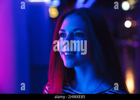 Junge weiße Frau in gestreiften Kleidern, lächelnd und schaut nach draußen Stockfoto