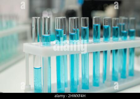 Reihe von mehreren Kolben oder Reagenzgläsern mit blauer Flüssigkeit am Arbeitsplatz eines modernen Arztes oder Wissenschaftlers im Labor Stockfoto