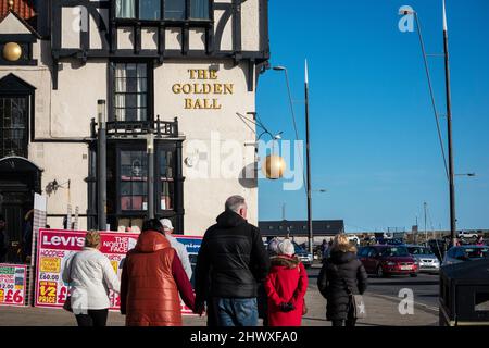 Menschenmassen, die an einer Kneipe in Scarborough, Yorkshire, entlang der Promenade spazieren Stockfoto