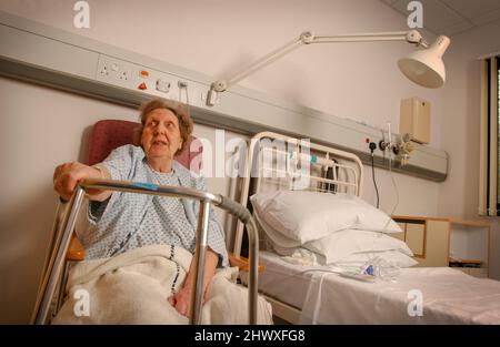 Eine ältere Dame an ihrem Bett in einer Krankenstation. (MODEL VERÖFFENTLICHT) Stockfoto