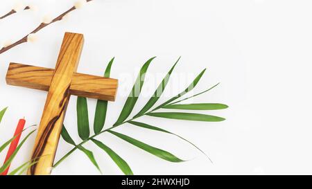 Ostern Religion Komposition mit Holzkreuzigung, Palmblatt, Weidenzweig und rote Kirche Kerze auf weißem Hintergrund mit Kopierraum. Das Konzept Stockfoto