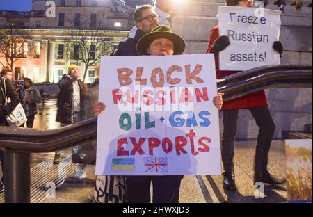 London, Großbritannien. 2.. März 2022. Ein Protestler hält ein Plakat mit der Aufforderung, die russischen Öl- und Gasexporte zu blockieren. Hunderte von Menschen versammelten sich am achten Tag der Proteste auf dem Trafalgar Square, während der Krieg in der Ukraine andauert. Stockfoto