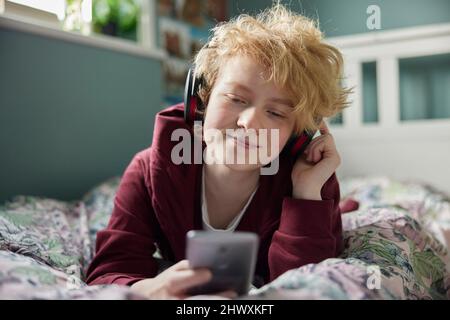 Teenager-Mädchen Mit Kabellosen Kopfhörern Hören Von Musik, Die Von Einem Mobiltelefon Zu Hause Aus Dampft Stockfoto