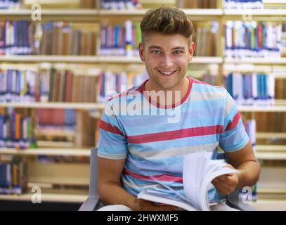 Einen ruhigen Ort zum Lernen finden. Porträt eines hübschen jungen Studenten, der in der Bibliothek studiert. Stockfoto
