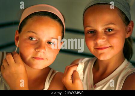 Zwei Mädchen überprüfen ihre Gesichter auf Flecken. (MODELL FREIGEGEBEN) Stockfoto