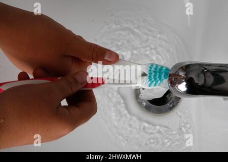 Zwei Mädchen waschen ihre Zahnbürsten unter fließendem Wasser Stockfoto