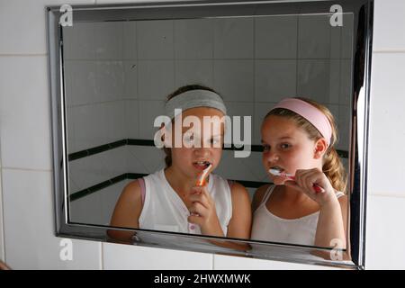 Zwei Mädchen, die sich die Zähne putzen. (MODELL FREIGEGEBEN) Stockfoto