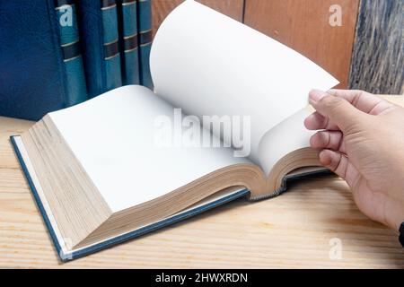 Nahaufnahme der Hand öffnen Sie das Buch auf einem Holztisch Stockfoto