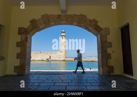 Rethymno, Kreta, Griechenland - 30.. Juni 2021: Person, die entlang der Kosten von Rethymno, das Leuchthaus im Hintergrund, geht Stockfoto