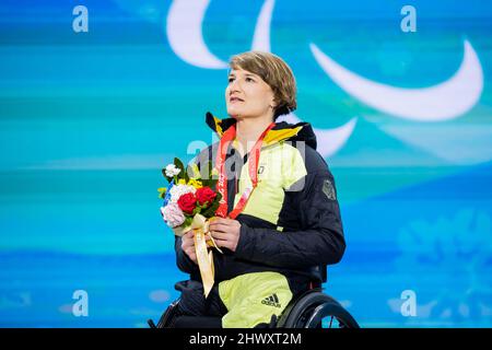 Peking, China. 08. März 2022. Paralympics, para Alpine Skiing, Frauen, Super Combined Sitting, Preisverleihung Yanqing Medals Plaza, Anna-Lena Forster aus Deutschland, hält ihre Goldmedaille bei der Preisverleihung und singt zusammen mit der Nationalhymne. Quelle: Christoph Soeder/dpa/Alamy Live News Stockfoto