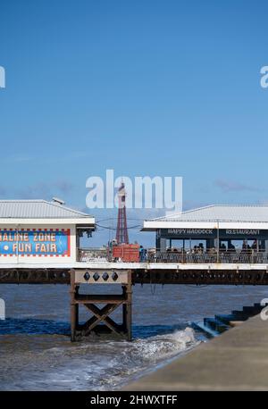 Blackpool Tower, das Wahrzeichen des beliebten Badeortes Blackpool, Lancashire, mit Gebäuden am South Pier im Vordergrund Stockfoto