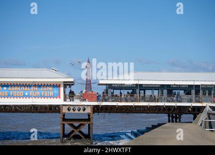 Blackpool Tower, das Wahrzeichen des beliebten Badeortes Blackpool, Lancashire, mit Gebäuden am South Pier im Vordergrund Stockfoto