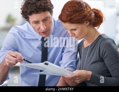 Sie kann immer auf seine Hilfe zählen. Junge Geschäftsleute diskutieren Arbeitsdokumente. Stockfoto