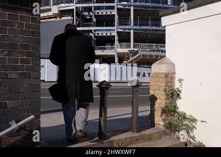 Ein Fußgänger durchläuft eine Lücke, die alte Mauern gegenüber neuen Immobilien am neu entwickelten Battersea Power Station in Nine Elms, am 7.. März 2022 in London, England, führt. Stockfoto